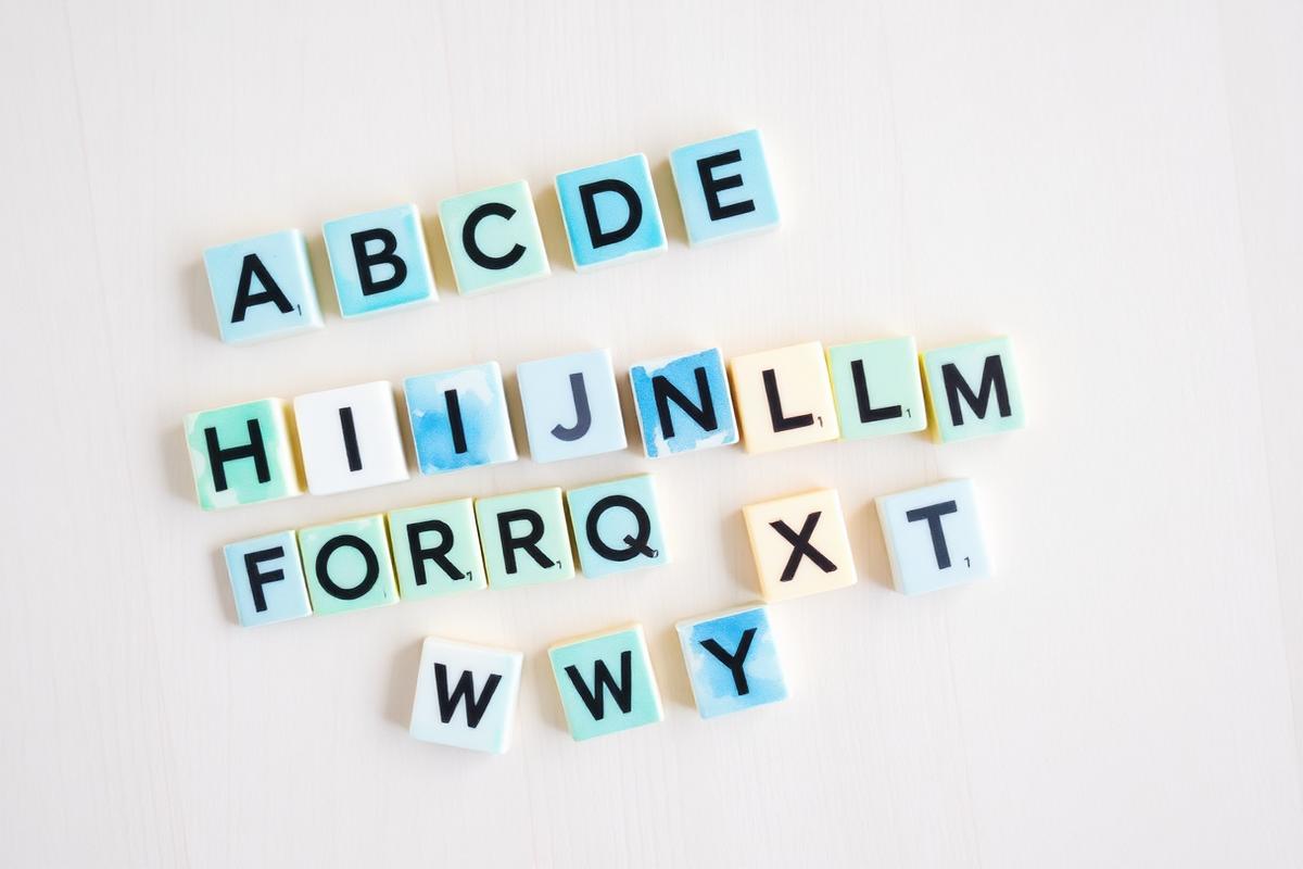 Colorful alphabet letter tiles arranged on a light wooden surface